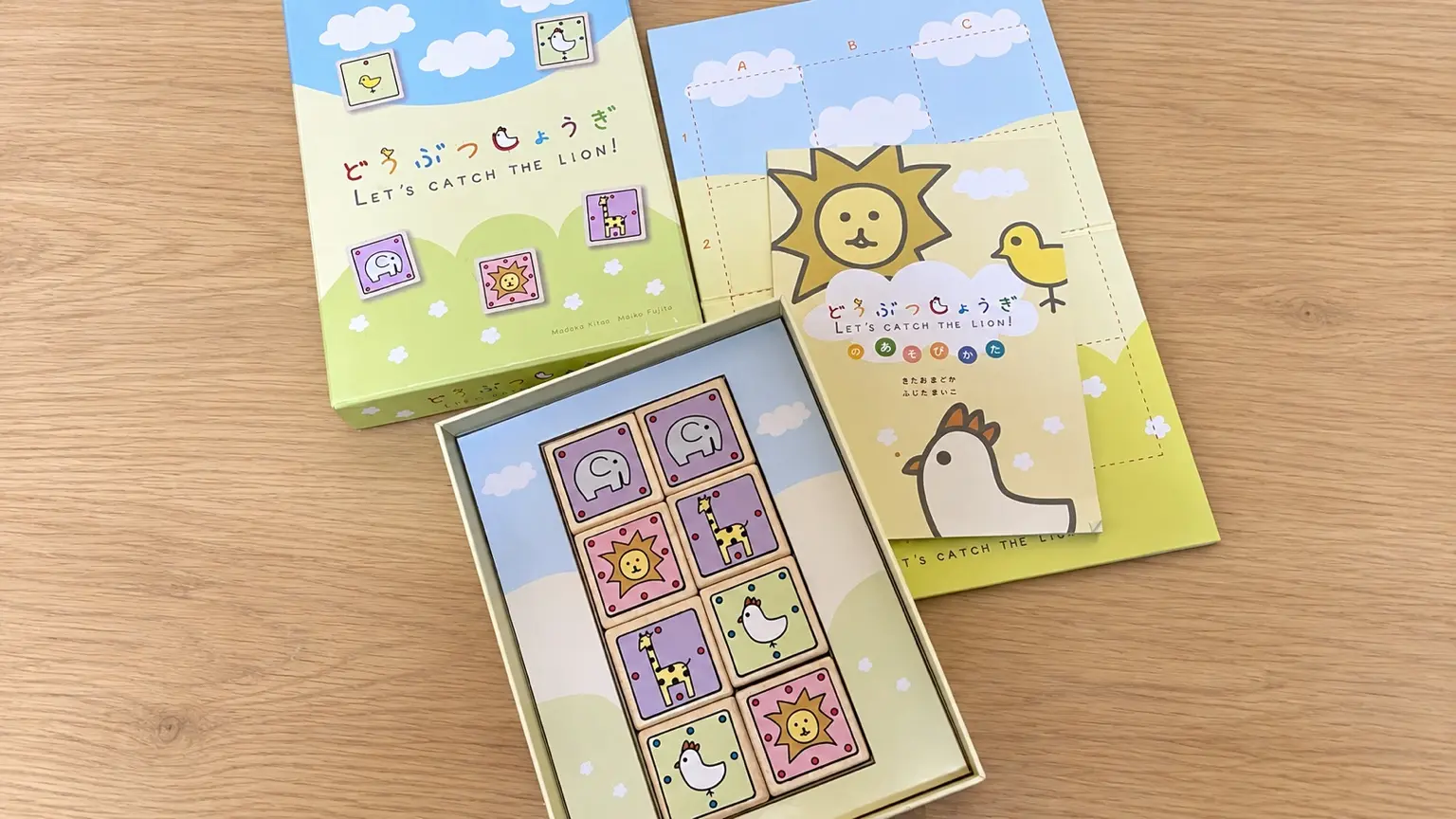 木製テーブルに並べたどうぶつしょうぎの盤、動物の駒、外箱、遊び方冊子