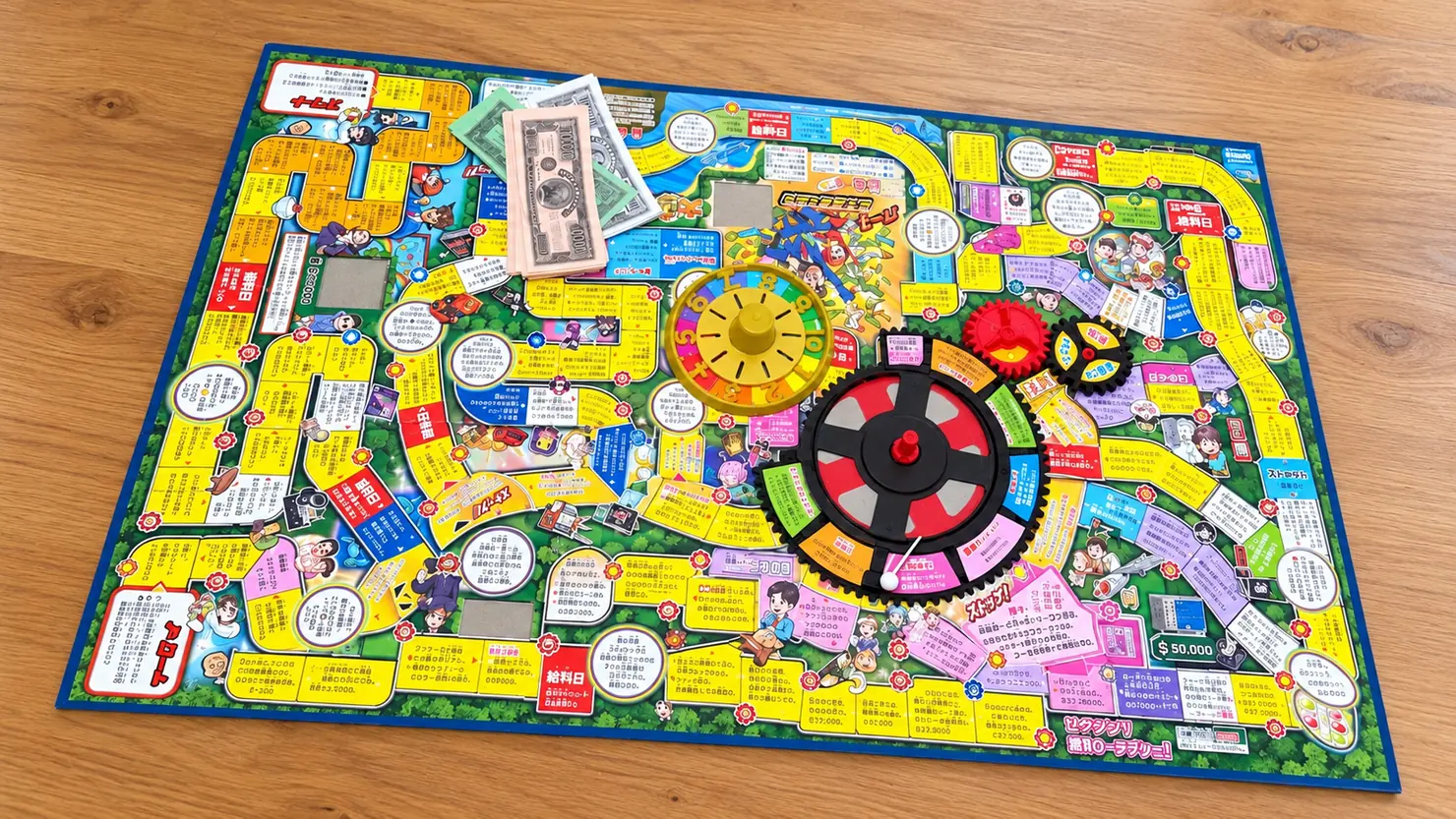 人生ゲームのカラフルな盤面とルーレット、紙幣などの付属品