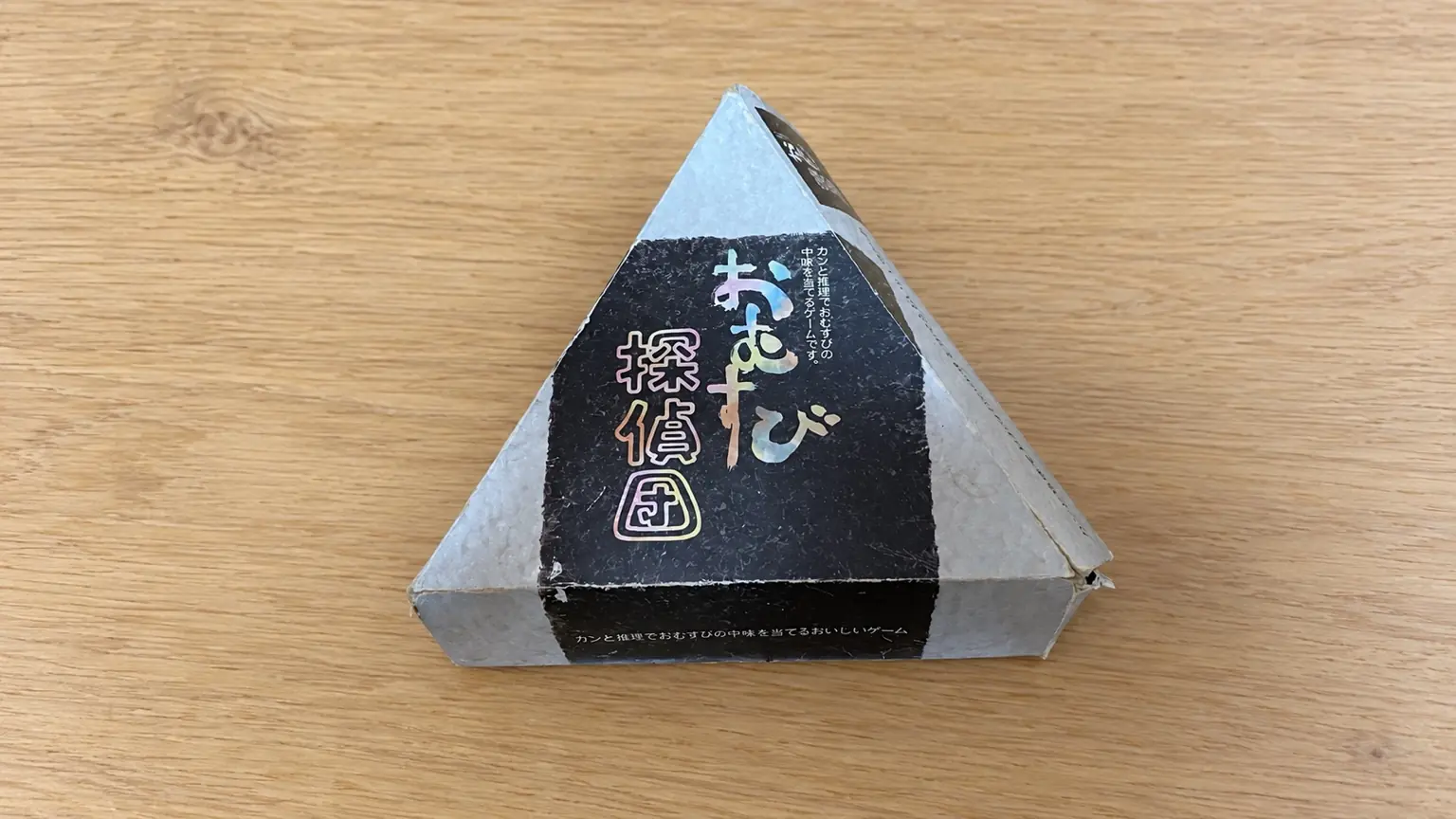 木製テーブルに置かれた、おにぎり型ゲーム「おむすび探偵団」の箱