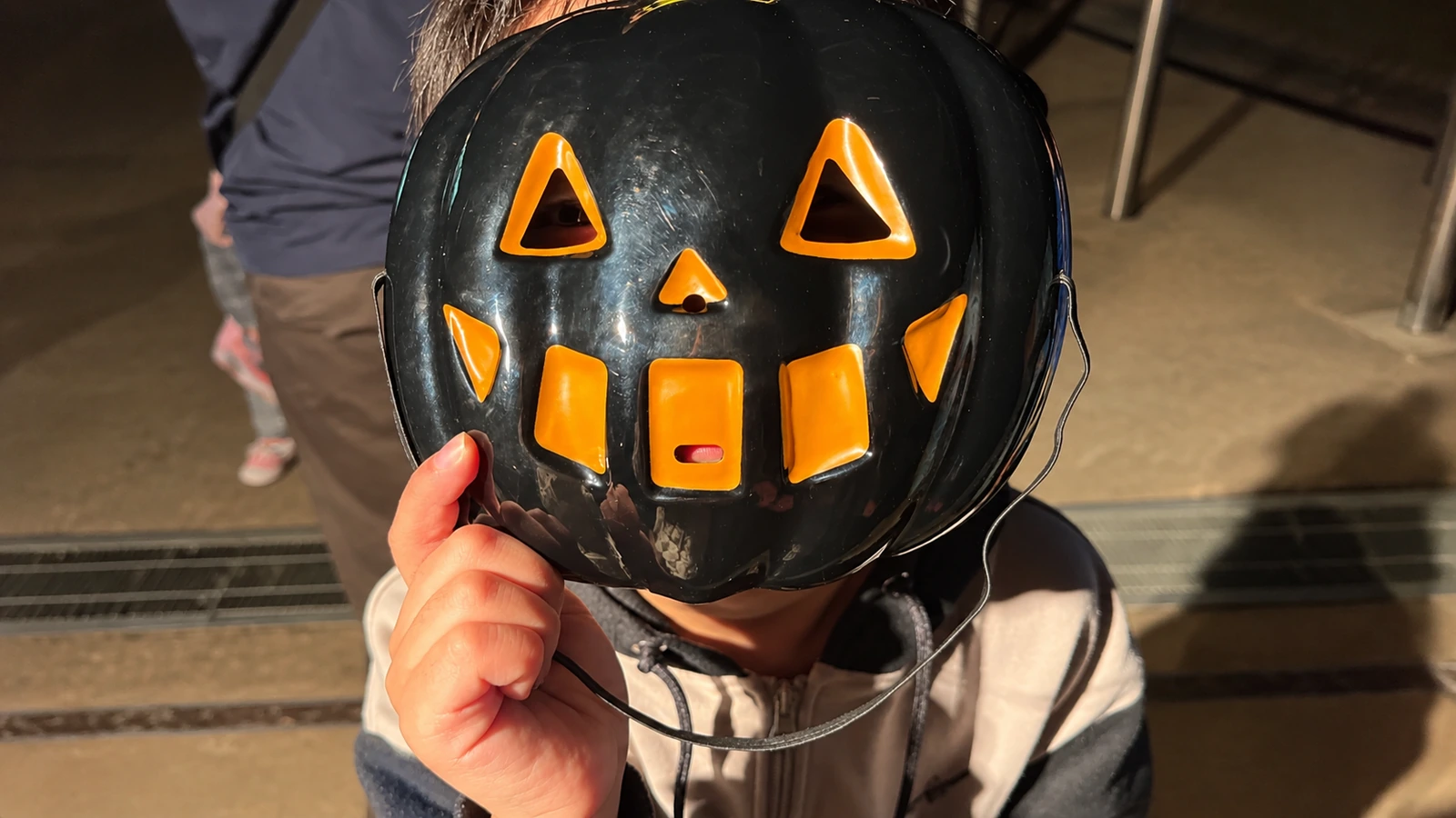 ハロウィンの黒いかぼちゃのお面を顔の前に持つ子ども